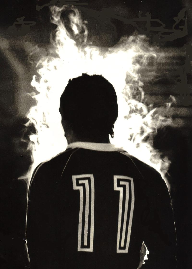 Black-and-white photo from behind of a player in a number 11 shirt, surrounded by smoke