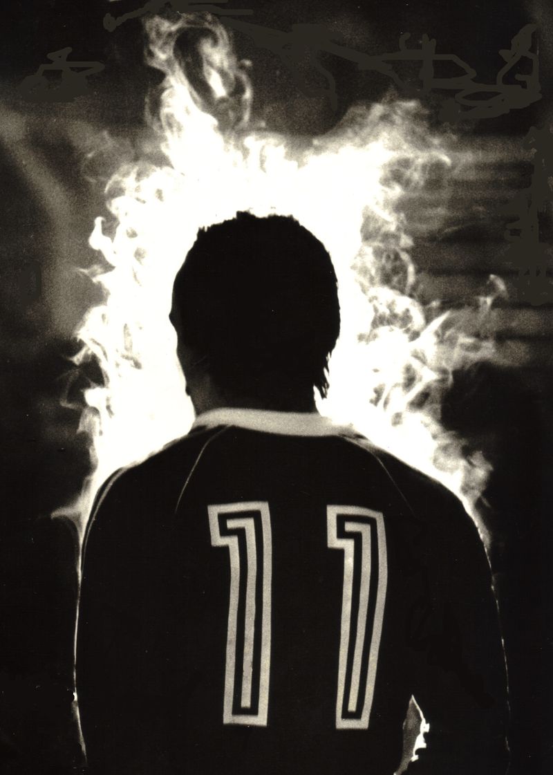 Black and white photo from behind of José Costa in the Portugal No. 11 shirt, surrounded by smoke