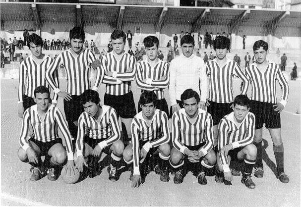 Black and white photo of a young team in striped shirts, seven standing and five crouching